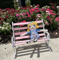 Alice rag doll sitting on bench outside