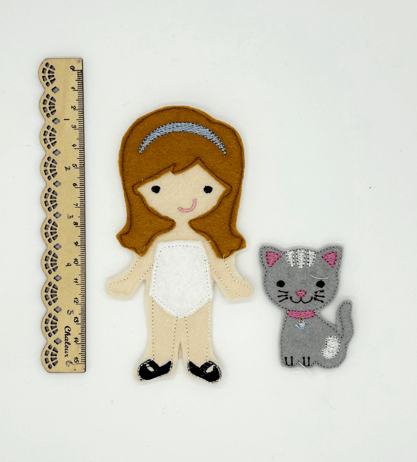 Felt "paper style" doll with cat, beside ruler for scale